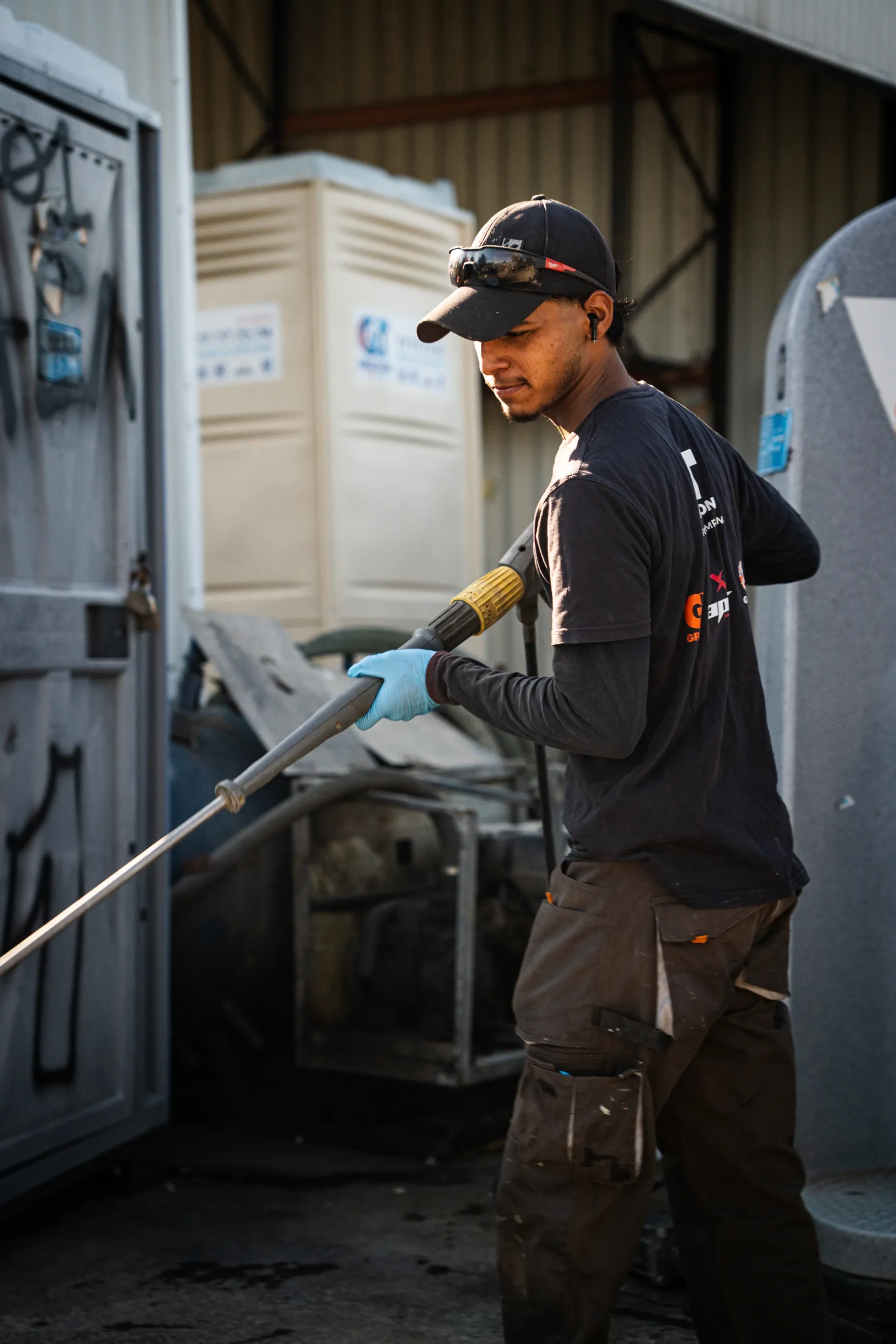 Greson Easy Loo technician pressure washing a portable toilet at the servicing yard